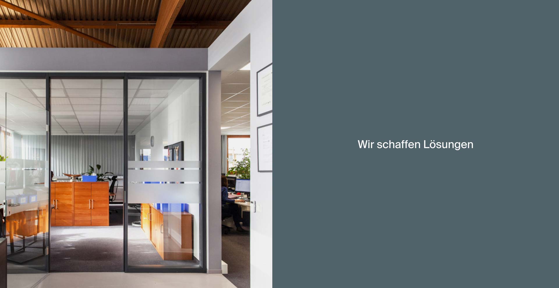 Büro mit Glastür zeigt Innenraum mit Holzmöbeln. Rechts auf grauem Hintergrund steht der Text: "Wir schaffen Lösungen".